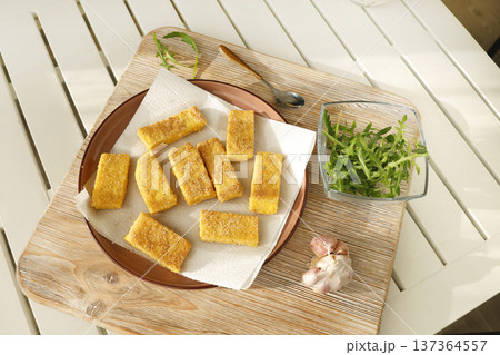 Sliced pieces of fried hard polenta on plate on table. Cornmeal in kitchen. Ingredients and traditional Italian cuisine. 137364557