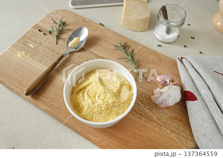 Corn flour in white ceramic bowl on wooden cutting board in kitchen. Parmesan and rosemary. Ingredients for polenta. Traditional Italian cuisine. Corn flour in white ceramic bowl on wooden cutting board in kitchen. Parmesan and rosemary. Ingredients for polenta. Traditional Italian cuisine. 137364559