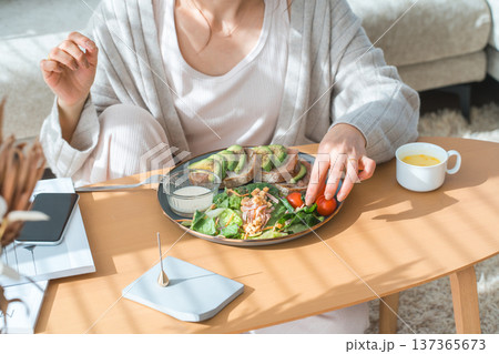 リビングテーブルで食事をするおしゃれな若いアジア人女性 リビングテーブルで食事をするおしゃれな若いアジア人女性 137365673