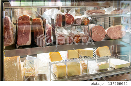 ショーケースに並ぶ生ハムのブロックと輸入チーズ イタリアン食材店やデリカテッセンの店頭 ショーケースに並ぶ生ハムのブロックと輸入チーズ イタリアン食材店やデリカテッセンの店頭 137366652