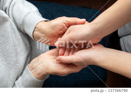 Young caregiver holding elderly person's hands showing compassion and support in home care Young caregiver holding elderly person's hands showing compassion and support in home care 137366790