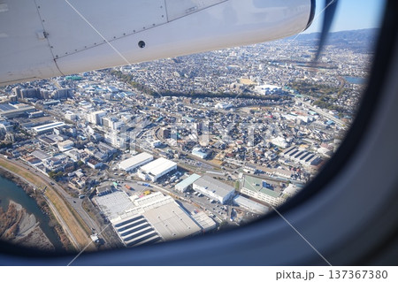 プロペラ機の窓から眺める市街地の俯瞰風景 137367380