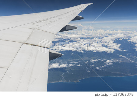 View of the plane's wing and beautiful clouds through the window during the flight. View of the plane's wing and beautiful clouds through the window during the flight. 137368379
