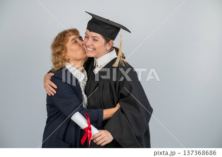 Portrait of Caucasian woman in graduation gown with her mother. Portrait of Caucasian woman in graduation gown with her mother. 137368686