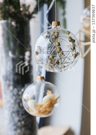 Decorative transparent ornaments hang elegantly, showcasing natural materials in a stylish indoor setting during winter 137369637