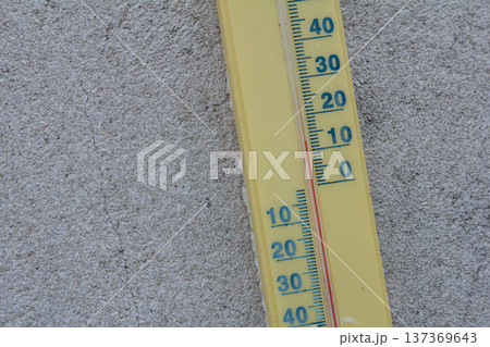 Thermometer displaying temperature in Celsius on a textured gray wall during a sunny day without any clouds in the sky Thermometer displaying temperature in Celsius on a textured gray wall during a sunny day without any clouds in the sky 137369643