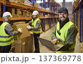 Warehouse inventory management with laptop as workers handle boxes on shelving 137369778