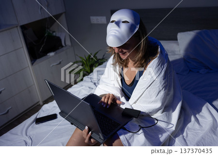 Woman in Mask Using Laptop on Bed, Focusing on Digital Privacy and Data Protection Woman in Mask Using Laptop on Bed, Focusing on Digital Privacy and Data Protection 137370435