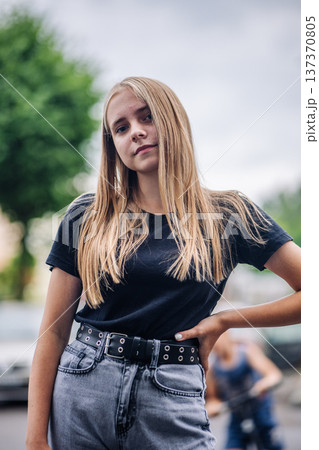 Blonde teen girl posing confidently with street style, expressing individuality outdoors Blonde teen girl posing confidently with street style, expressing individuality outdoors 137370805