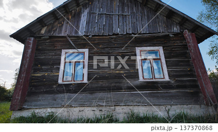 Abandoned rustic wooden house facade standing in a rural field with old windows Abandoned rustic wooden house facade standing in a rural field with old windows 137370868