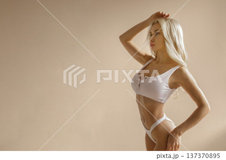 Attractive slim woman in white lingerie posing in studio, fitness body and beauty concep Attractive slim woman in white lingerie posing in studio, fitness body and beauty concep 137370895