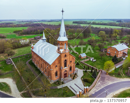 Neogothic brick church with steeple in a rural village landscape, aerial view 137370957
