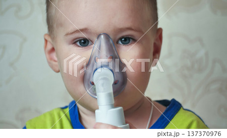 Child receiving respiratory treatment with nebulizer mask for breathing difficulty 137370976