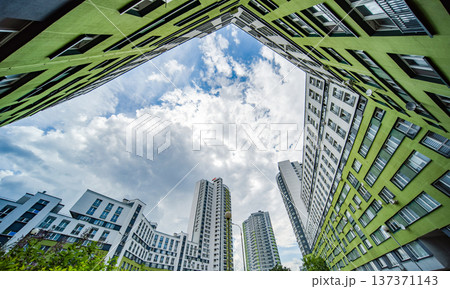 Architecture looking up at modern green and white residential buildings against cloudy sky Architecture looking up at modern green and white residential buildings against cloudy sky 137371143
