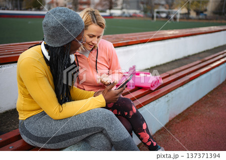 Two diverse women training planning with tablet at stadium Two diverse women training planning with tablet at stadium 137371394