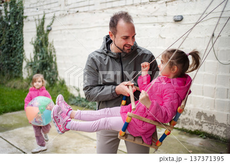 Father playing with his two young daughters in the backyard Father playing with his two young daughters in the backyard 137371395
