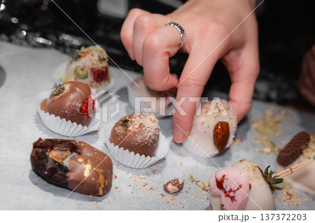 Hands Decorating Chocolate Covered Strawberries With Toppings 137372203