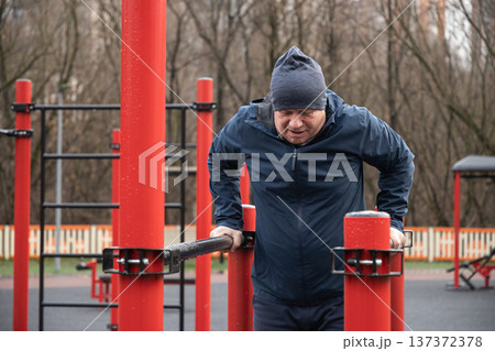 Man Performing Dips on Parallel Bars Outdoors. Training Outdoors 137372378