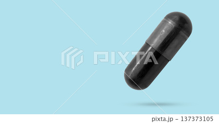 Black medicine pill activated charcoal capsule float on blue background 137373105