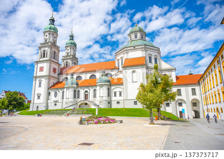 St. Lorenz Basilica showcases its stunning baroque architecture against a bright blue sky in Kempten. Visitors enjoy the peaceful surroundings and admire the historic structure during daytime. 137373717