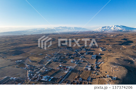 Mountain village from above, surrounded by barren hills and snow peaks 137374206