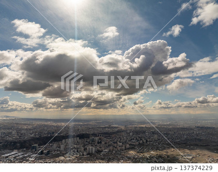 Aerial view of a city under dynamic sky with sun rays piercing through clouds 137374229