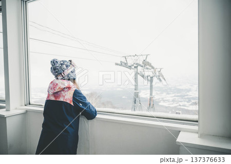 窓からスキー場のゲレンデを見る若い女性 137376633