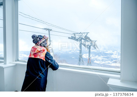 窓からスキー場のゲレンデを見る若い女性 137376634