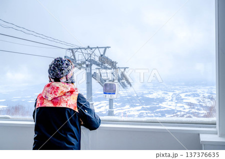 窓からスキー場のゲレンデを見る若い女性 137376635