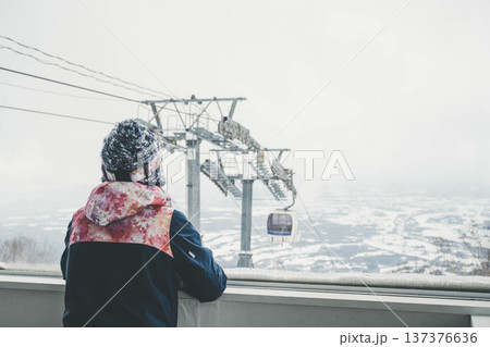 窓からスキー場のゲレンデを見る若い女性 137376636