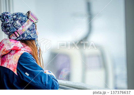窓からスキー場のゲレンデを見る若い女性 137376637