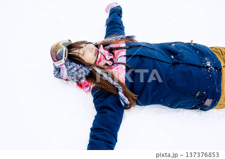 スキーウェアを着てゲレンデで雪と戯れる若い女性 137376853