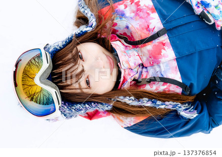 スキーウェアを着てゲレンデで雪と戯れる若い女性 137376854