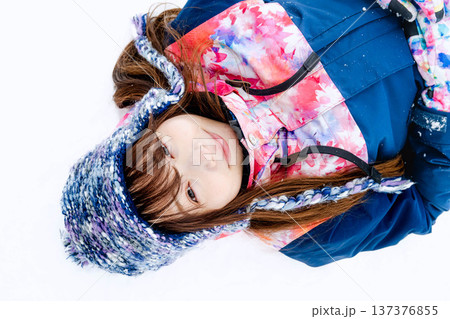 スキーウェアを着てゲレンデで雪と戯れる若い女性 スキーウェアを着てゲレンデで雪と戯れる若い女性 137376855