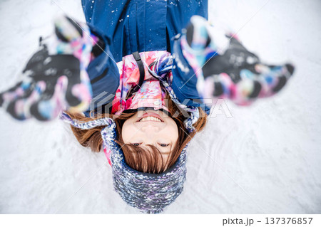 スキーウェアを着てゲレンデで雪と戯れる若い女性 137376857