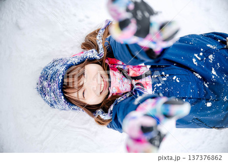 スキーウェアを着てゲレンデで雪と戯れる若い女性 137376862