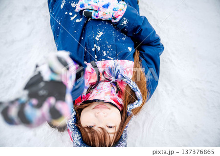 スキーウェアを着てゲレンデで雪と戯れる若い女性 137376865