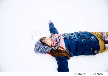 スキーウェアを着てゲレンデで雪と戯れる若い女性 スキーウェアを着てゲレンデで雪と戯れる若い女性 137376872