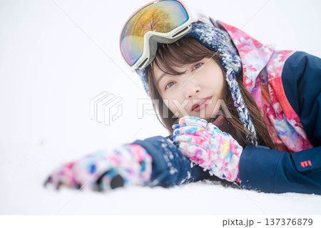 スキーウェアを着てゲレンデで雪と戯れる若い女性 137376879