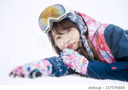 スキーウェアを着てゲレンデで雪と戯れる若い女性 スキーウェアを着てゲレンデで雪と戯れる若い女性 137376880