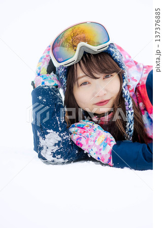 スキーウェアを着てゲレンデで雪と戯れる若い女性 137376885