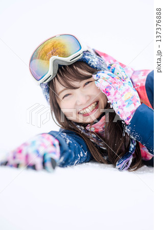 スキーウェアを着てゲレンデで雪と戯れる若い女性 137376888