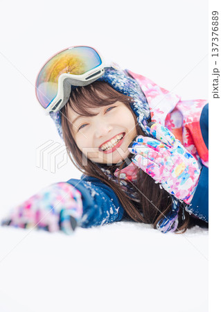 スキーウェアを着てゲレンデで雪と戯れる若い女性 137376889