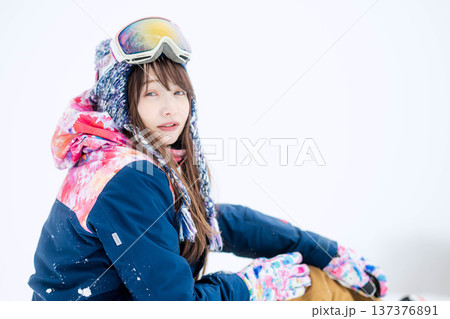 スキーウェアを着てゲレンデで雪と戯れる若い女性 137376891