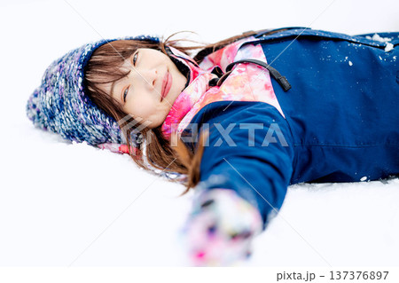 スキーウェアを着てゲレンデで雪と戯れる若い女性 137376897