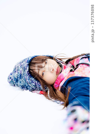 スキーウェアを着てゲレンデで雪と戯れる若い女性 137376898