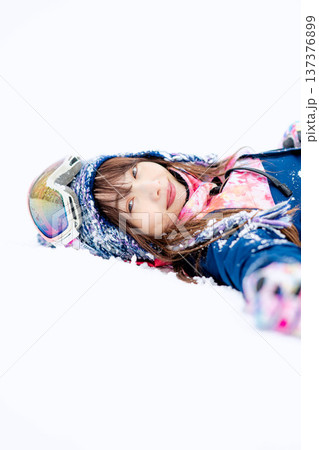スキーウェアを着てゲレンデで雪と戯れる若い女性 137376899