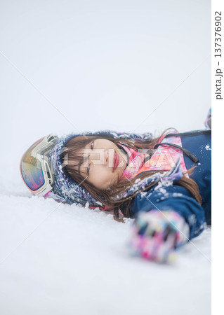 スキーウェアを着てゲレンデで雪と戯れる若い女性 137376902