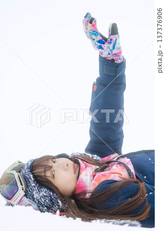 スキーウェアを着てゲレンデで雪と戯れる若い女性 137376906