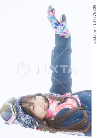 スキーウェアを着てゲレンデで雪と戯れる若い女性 スキーウェアを着てゲレンデで雪と戯れる若い女性 137376909